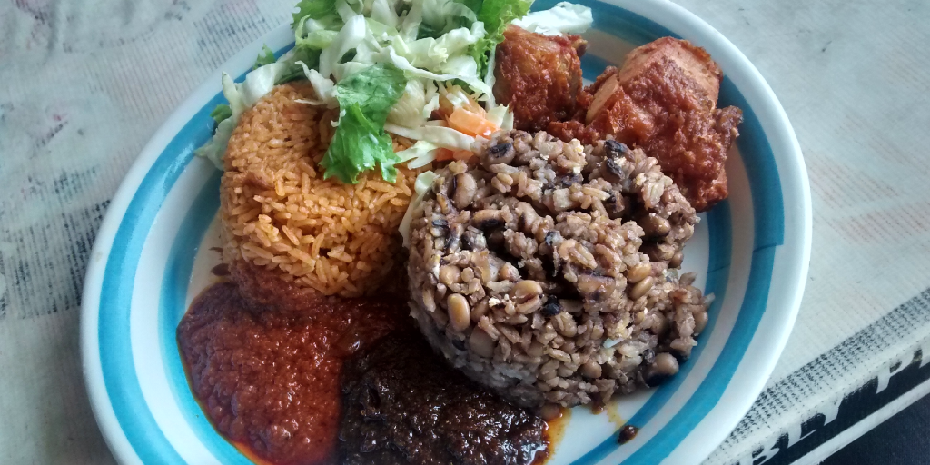 A plate filled with waakye, jollof rice and other traditional Ghanaian food. 