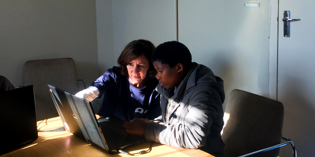 A GVI volunteer helps a women use a computer. 