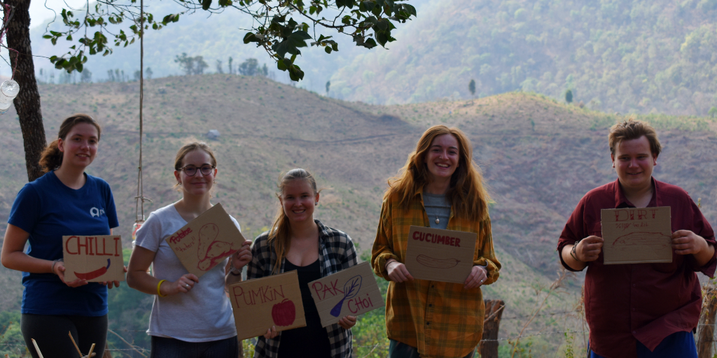 GVI volunteers hold signs of seeds that were planted in the garden. 
